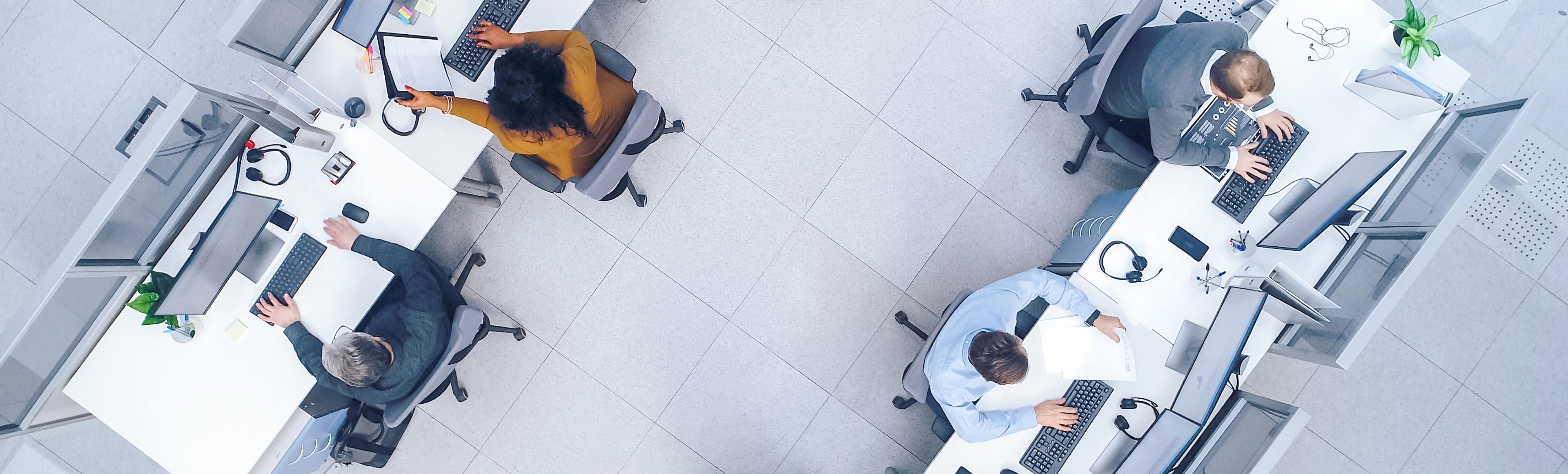 overhead view of 4 people working at desks in an office