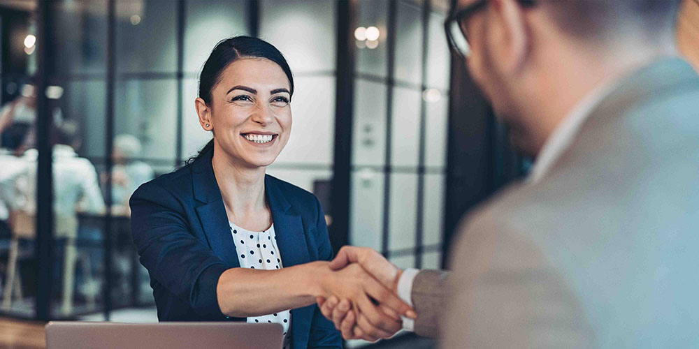 A smiling business woman shaking hands with a business man