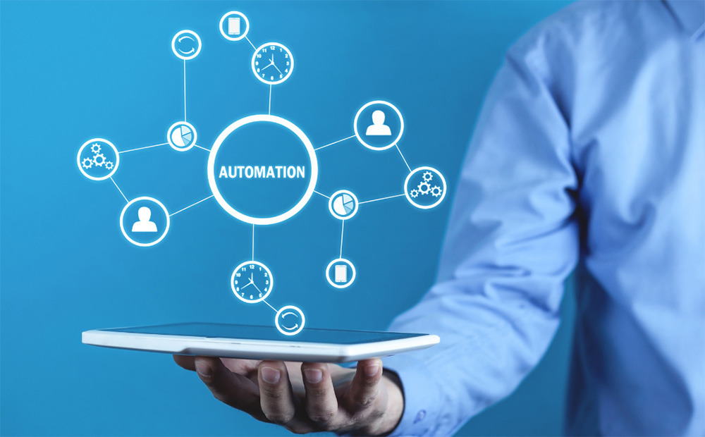 mans hand holding a tablet with illustration overlaid with the word automation in a network of technology icons